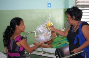 Chavela Castillo pone en manos de Gladisley González, mamá de la bebita, los elementos que componen la canastilla donada. Foto: Barreras Ferrán.