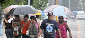 Transeúntes caminan por la calle 23 protegidos por sombrillas bajo las intensas lluvias que azotan La Habana, Cuba, el 5 de junio de 2013. AIN FOTO/Roberto MOREJÓN RODRÍGUEZ