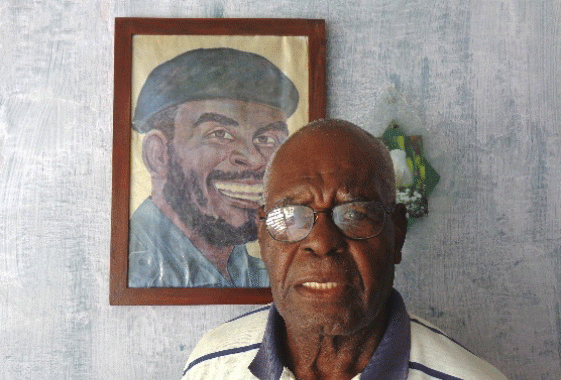 Elmo Bárcenas, junto a un retrato de su hermano Emilio Bárcenas (Tanganica). Foto: Del autor