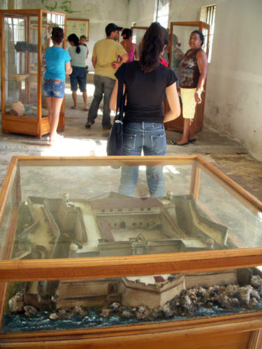 En primer plano, la maqueta del castillo estilo medieval, cuadrado y abaluartado. Su construcción concluyó en 1745, pero en 1762 fue incendiado para que no pudiera ser empleado en la toma de La Habana por los ingleses. Años después fue empleada como prisión y eso requirió que se le hicieran transformaciones constructivas que han sido respetadas en la reconstrucción.