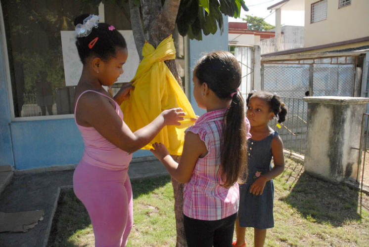Niños colocando una cinta amarilla en el tronco del árbol por la libertad los héroes cubanos. Foto: Agustín Borrego