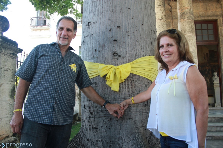 René González y Olga Salanueva atan una cinta amarilla en la ceiba del Templete. La Habana
