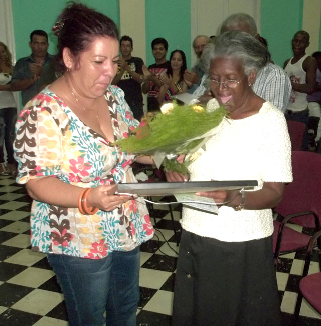 Leonor Somonte (a la derecha) recibe el reconocimiento entregado por Idalmis Gil, primera secretaria del comité municipal del Partido Comunista de Cuba en Ciro Redondo. Foto: José Luis Martínez Alejo.