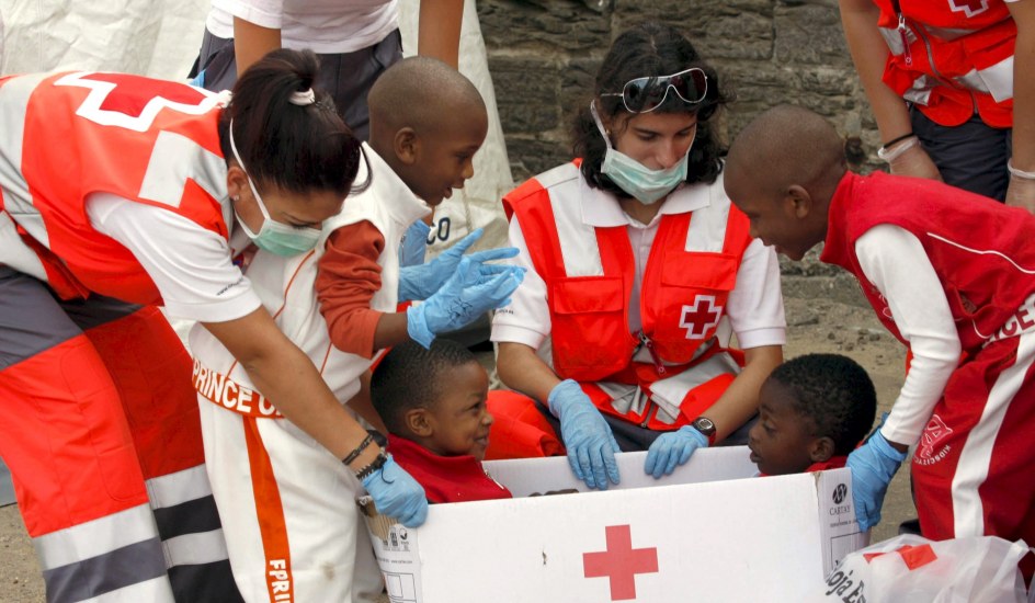 Foto de archivo en la que voluntarios de la Cruz Roja cuida y entretienen a unos niños (EFE)