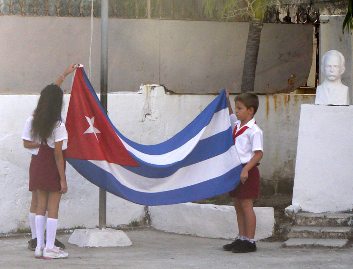 Izar la bandera cubana y cantar el himno son las primeras actividades que realizan los pioneros cubanos antes de comenzar la jornada docente.