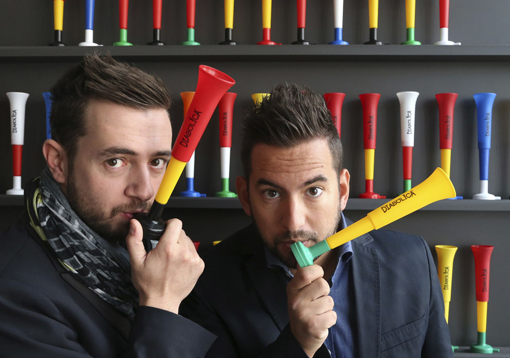 Los Empresarios belgas Fabio Lavalle (izquierda) y David Dos Santos posan con la trompeta "diabolica" en Mons, Bélgica, el 16 de mayo de 2014. Las ensordecedoras vuvuzelas estaban siempre presentes como telón de fondo de la Copa Mundial 2010 en Sudáfrica. Cuatro años después, dos empresarios belgas esperan llenar los estadios en Brasil con el sonido agudo de las trompetas de plástico llamadas "diabolica". Foto: Reuters / Francois Lenoir.