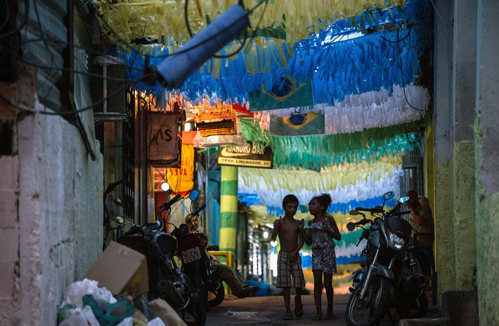 Dos niños caminan por una calle decorada con los colores de la selección brasileña en la favela Rocinha favela en Río de Janeiro el 9 de junio de 2014. Foto: Yasuyoshi Chiba/AFP/Getty Images.