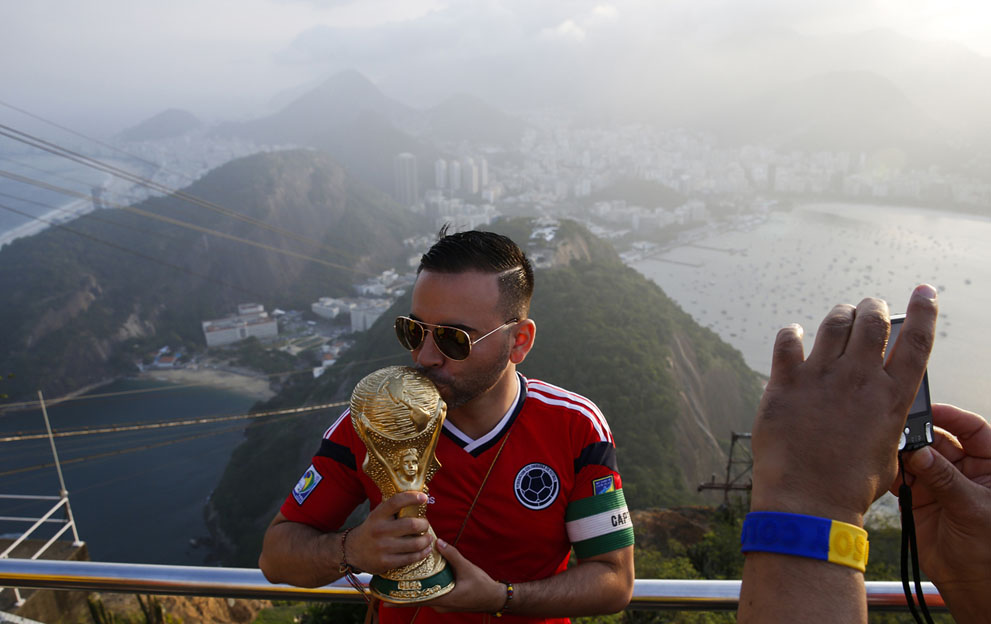 Un seguidor de Colombia besa una réplica de la Copa del Mundo en Río de Janeiro, al fondo la cima del Pan de Azúcar el 9 de junio de 2014. Foto: Reuters/Paul Hanna.