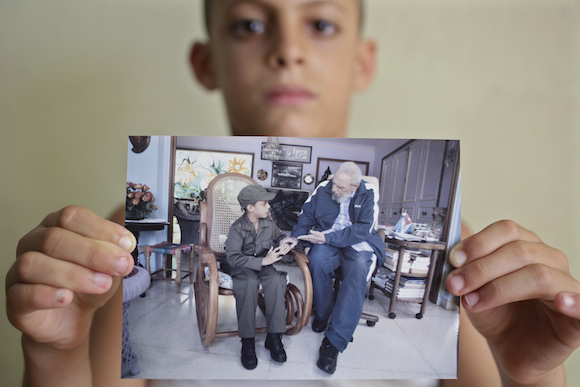 Eight-year-old Marlon Mendez, who claims to be an admirer of Cuba's former president Fidel Castro, holds a picture from him and Fidel Castro, in San Antonio de los Banos, outside Havana City