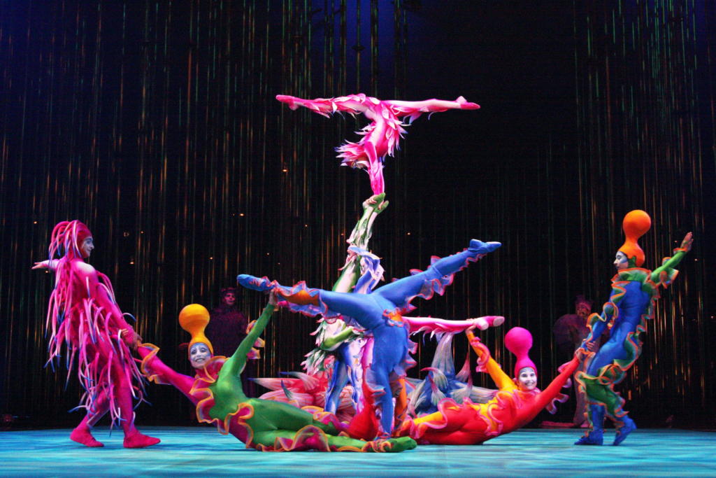 El elenco de Circo del Sol posee artistas de 25 nacionalidades. Para el show se han confeccionado 530 disfraces y contratado a 47 maquilllistas. Ya suman miles de horas de ensayo. 
