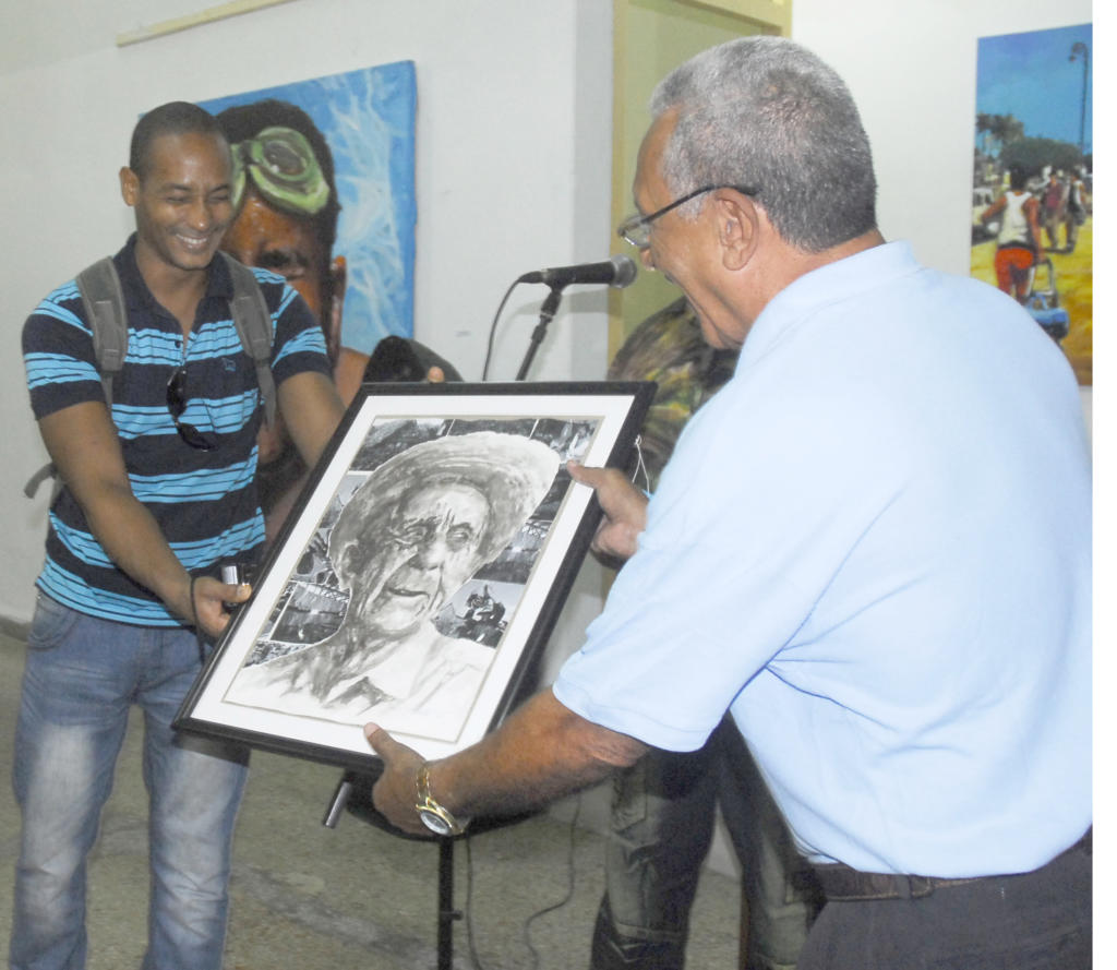 Expo de pintura por el día de la Cultura Cubana de Sanlly Vira Alarcón. Francis Copola, pintor que dona una de sus obras para la institución, recibe esta Raimundo Estrada Rodríguez, director del palacio de los Torcedores.  Palacio de Los Torcedores, Centro Habana. Foto: Agustín Borrego.