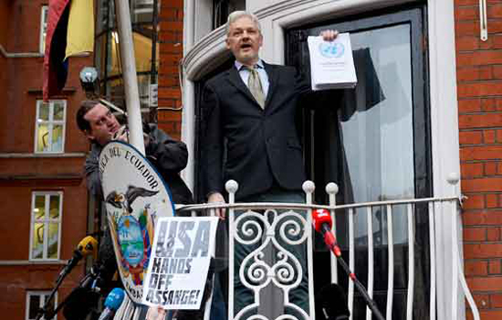 Julian Assange muestra, desde un balcón de la Embajada, el dictamen de la ONU, pero ni con ese argumento cejan sus perseguidores. Foto: AFP