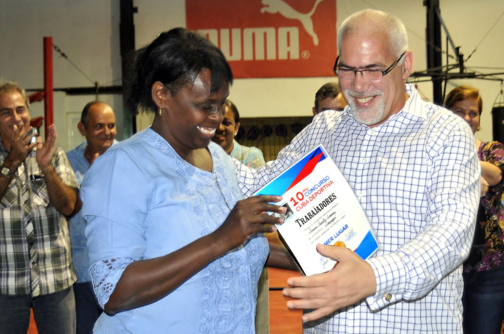 El Dr. Antonio Becali Garrido premia a la ganadora del X Concurso Cuba Olímpica, la cienfueguera Genara Padilla Jiménez. Foto: José Raúl Rodríguez Robleda.