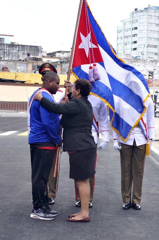 Olga Lidia Tapia, Miembro del Secretariado y Jefe del Departamento de Educación, Deportes y Ciencia del Comité Central del Partido, entregó la bandera cubana a Alfredo Despaigne.