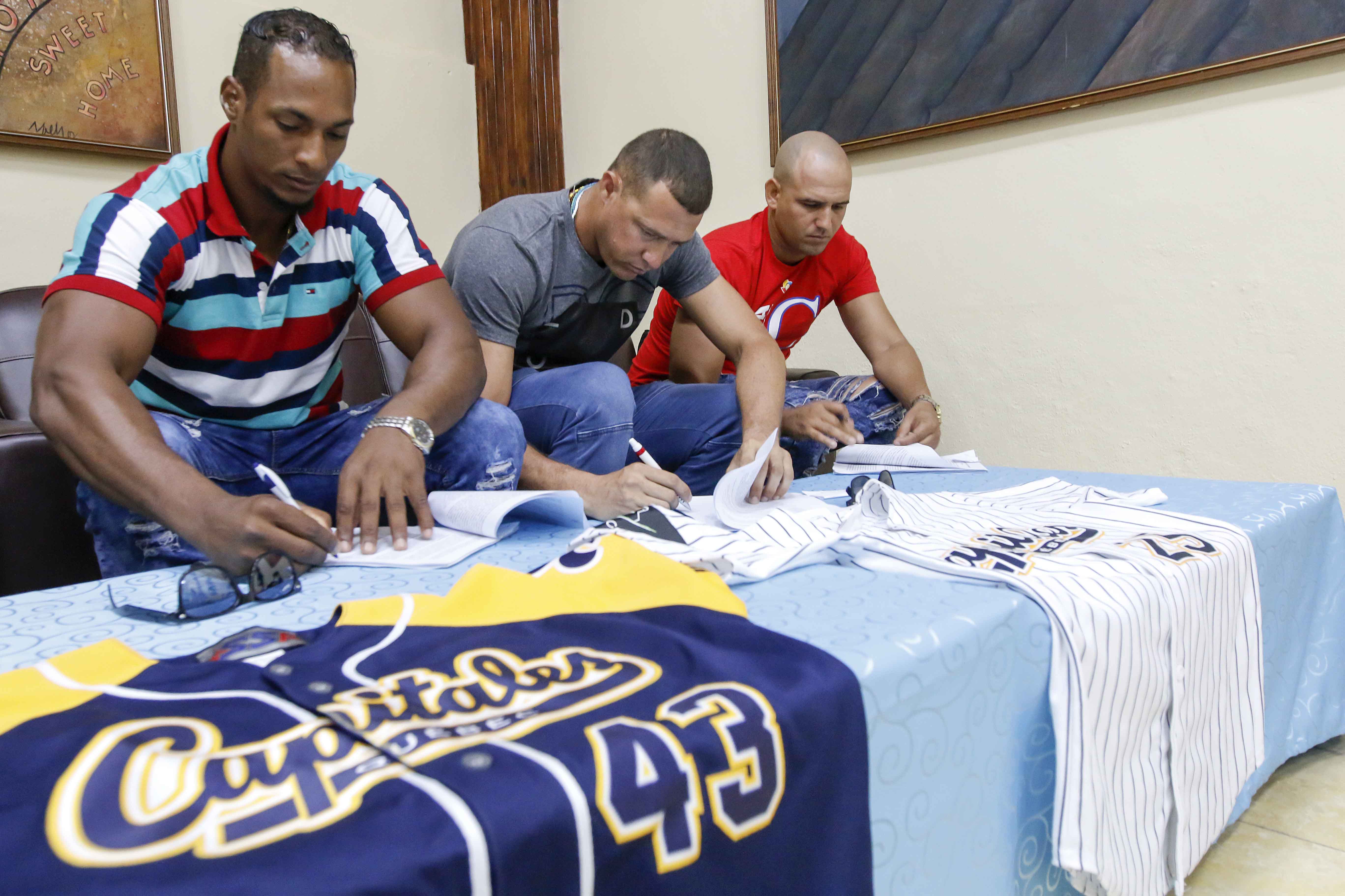 Yurisbel Gracial (I), Lázaro Blanco (C) y Yordan Manduley (D) durante la firma de contrato con el equipo Capitales de Québec en el Salón de Protocolos de la Federación Cubana de Béisbol, en el estadio Latinoamericano, en La Habana.. Foto: Roberto Morejón Rodríguez