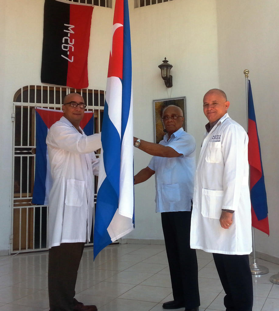 Momento en que ponen en manos del doctor Evelio Betancourt Tamayo la bandera cubana, símbolo que lo acompañará a la Primera Conferencia del SNTS. Foto: Cortesía de la Brigada Médica de Cuba en Haití.