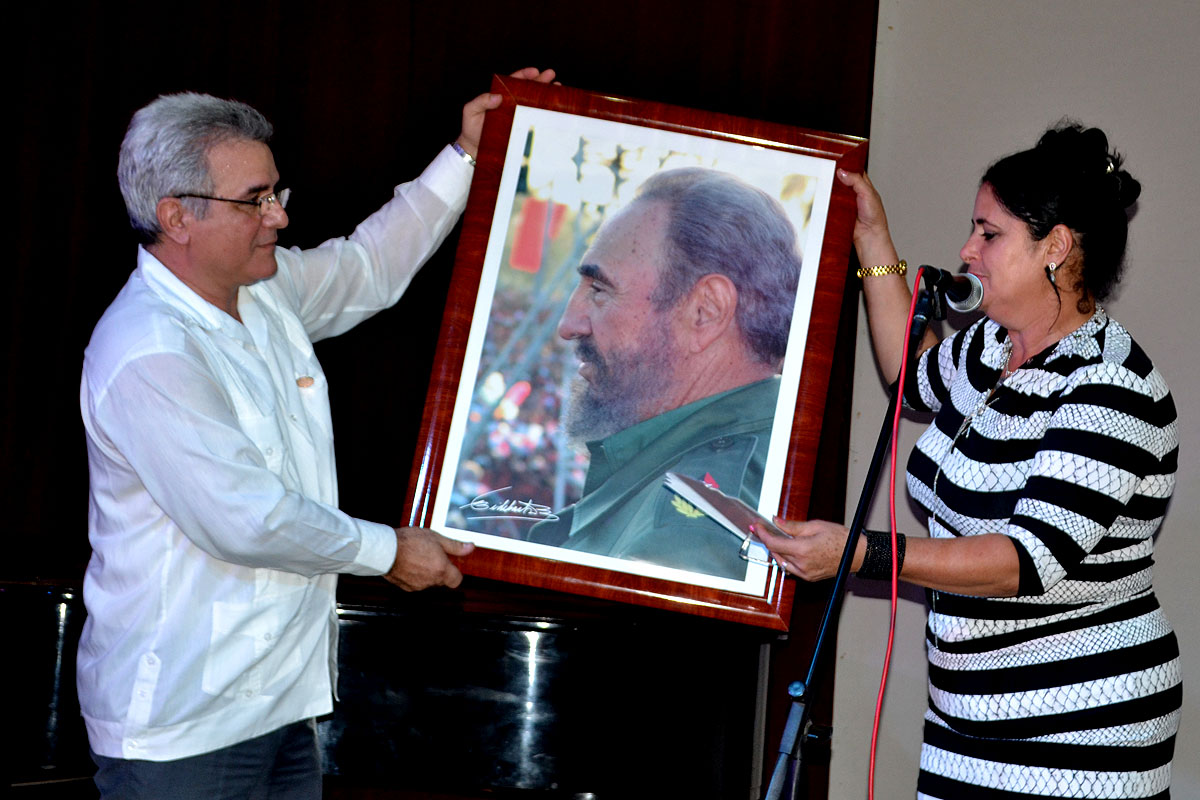 Consuelo Baeza, integrante del secretariado nacional de la CTC, entregó un cuadro con la imagen del Comandante en Jefe Fidel Castro a René González Barrios, presidente del IHC. Foto: Eddy Martin Díaz