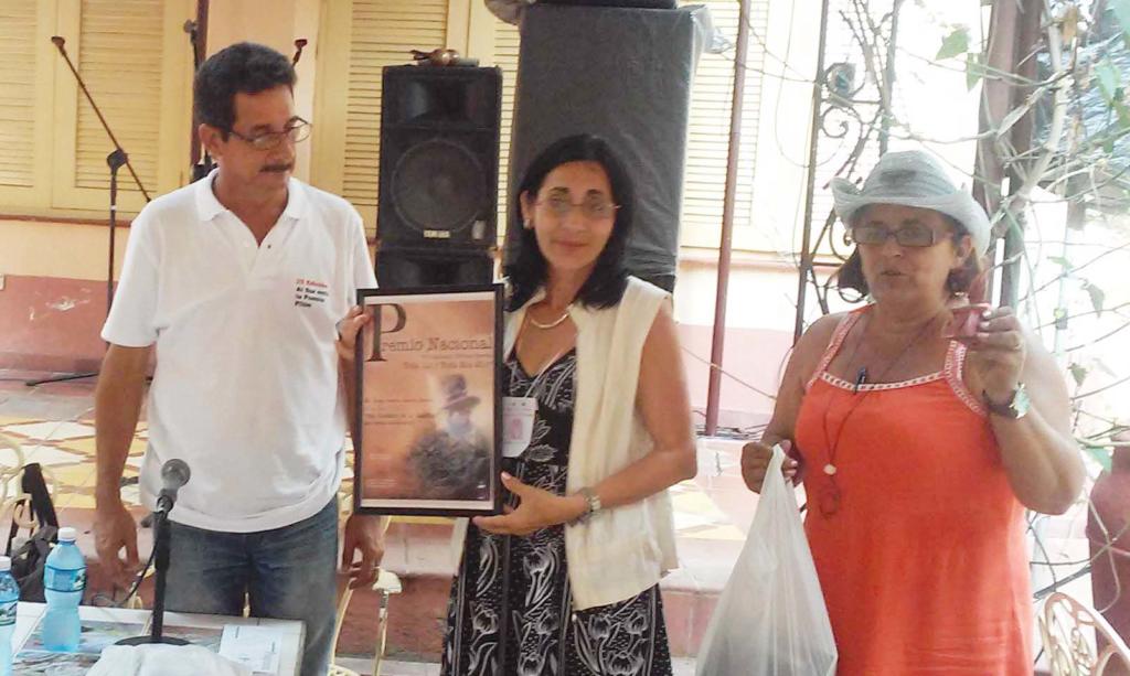 De izquierda a derecha Alejandro González, en nombre del jurado de décima escrita, entregó el premio a Luisa Oneida Landín, quien fue felicitada por Merari Mangly Carrillo, presidenta del Grupo Toda luz y toda mía. Foto: Karel Leyva