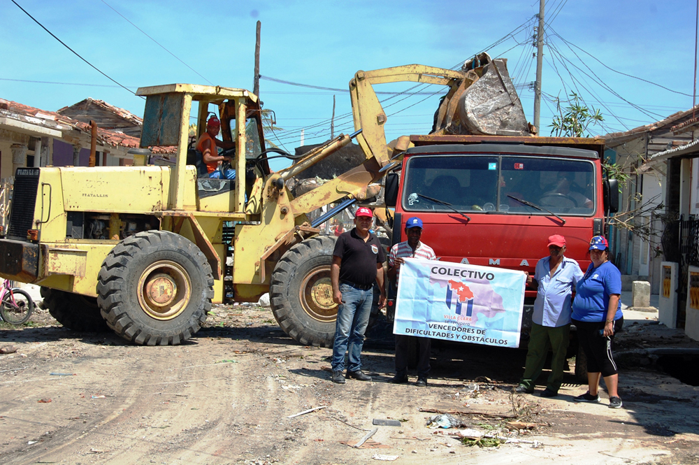 Carlos de Dios Oquendo, secretario general del SNTC (a la izquierda), entregó el estandarte que ratifica la condición de vencedores de dificultades y obstáculos a los constructores de la Ecoing 25 que laboran en Caibarién. Foto: Ramón Barreras Ferrán