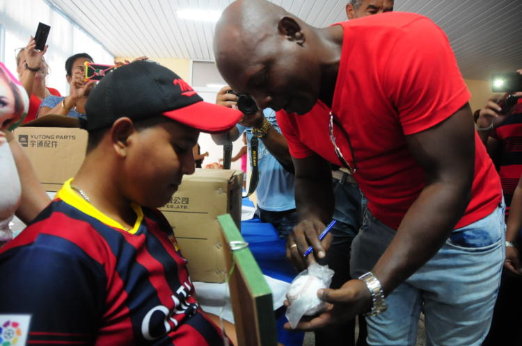 El pelotero Danel Castro, gloria del deporte en Las Tunas, firma una pelota y la entrega a uno de los niños acogidos. Foto: Ángel Chimeno Pérez