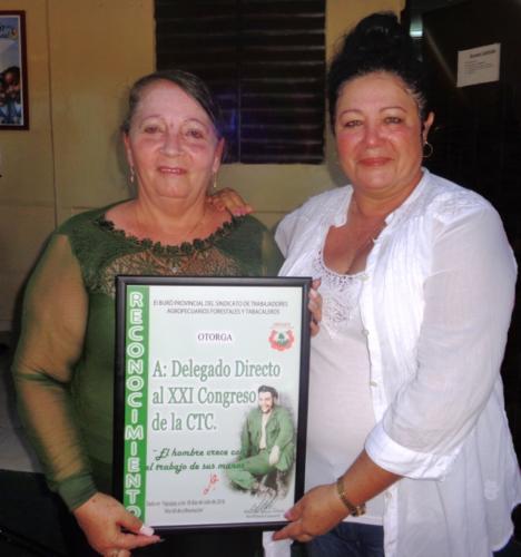 Mercy Rodríguez Crespo, secretaria general del Comité Provincial de la CTC en Sancti Spíritus, entregó el reconocimiento que acredita a María Elvira Dávila como la primera delegada directa de ese territorio al XXI Congreso de la organización obrera. Foto: Yuleiky Obregón Macías