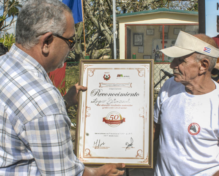 Néstor Bárbaro Hernández, secretario general del Sindicato Nacional de Trabajadores Agropecuarios, Forestales y Tabacaleros, entrega un diploma de reconocimiento a Lázaro Betancourt Almeida —a la derecha— por sus 50 años vinculado laboralmente a la ganadería El Cangre. | foto: Heriberto González Brito