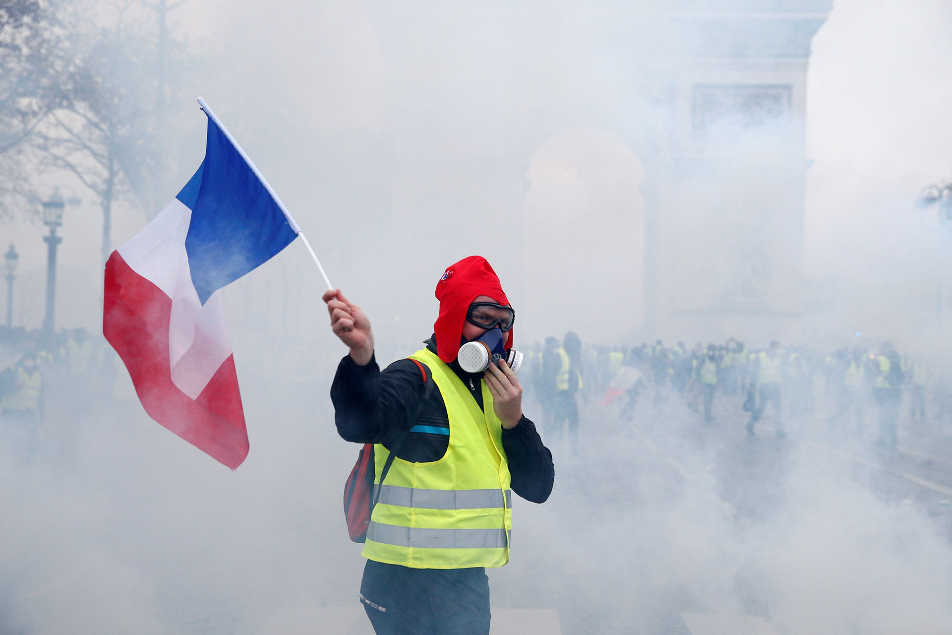 A protester wearing a yellow vest, a symbol of a French drivers' protest against higher diesel taxes, holds a French flag during clashes at the Place de l'Etoile near the Arc de Triomphe in Paris, France, December 1, 2018. REUTERS/Stephane Mahe