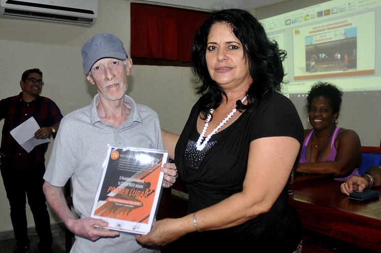 El primera lugar, Juan Nelson Vento Acosto, recibe el regalo de manos de Consuelo Baeza, miembro del Secretariado de la CTC Nacional. Foto: José Raúl Rodríguez Robleda