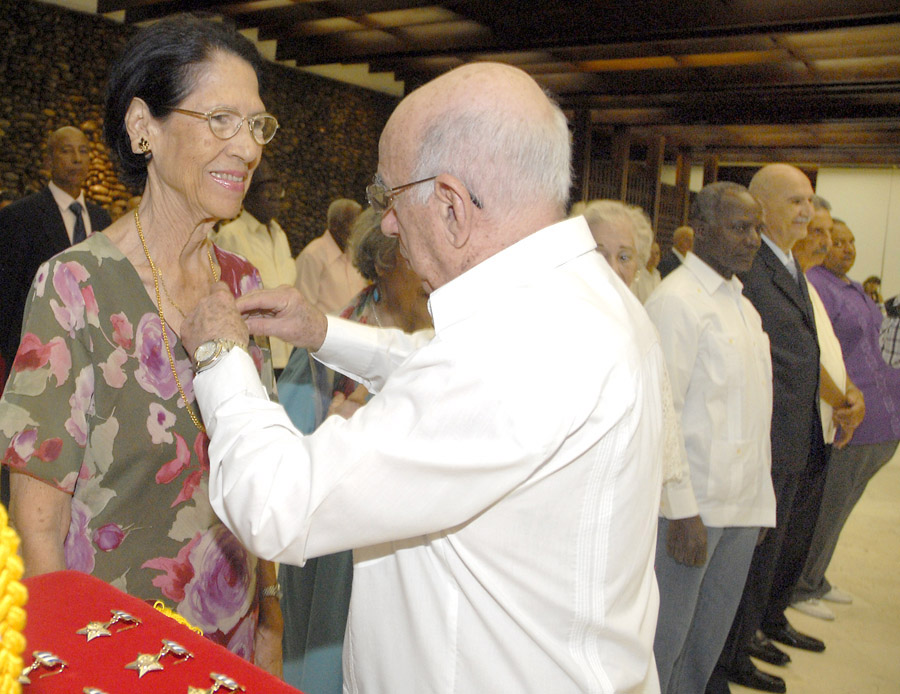 José Ramón Machado Ventura, Segundo Secretario del Comité Central del PCC, coloca en su pecho el Título de Heroína del Trabajo de la República de Cuba. Foto: Archivo Trabajadores