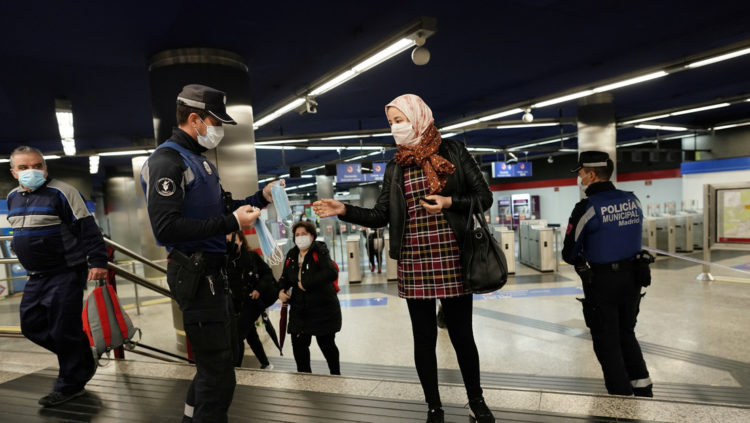 Fuerzas de seguridad reparten mascarillas a la entrada del metro, Madrid, 13 de abril de 2020. Foto Juan Medina / Reuters