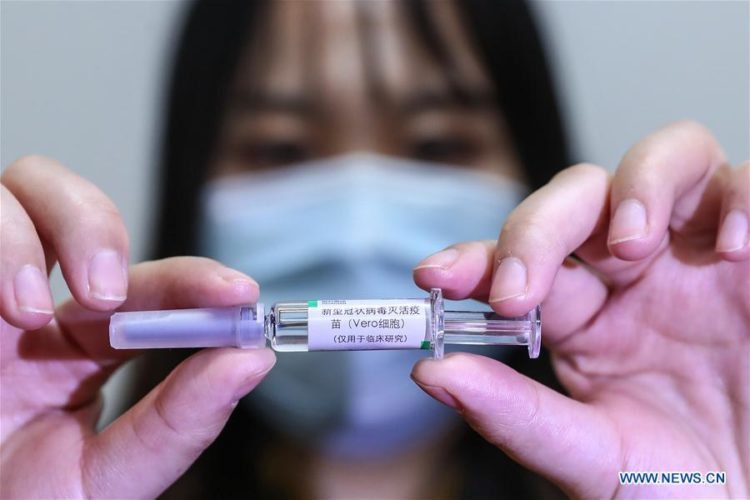 Imagen del 10 de abril de 2020 de una trabajadora presentando una muestra de la vacuna inactiva de COVID-19 en una planta de producción de vacunas del Grupo Farmacéutico Nacional de China (Sinopharm), en Beijing, capital de China.