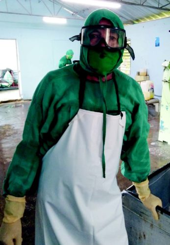 Protegido de pies a cabeza, con botas de goma, delantal, guantes, nasobucos y gorro, Rogelio asume el lavado de la ropa que se emplea en la zona roja del Hospital Militar de Camagüey. Foto: Gretel Díaz Montalvo