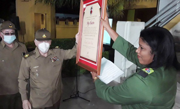 La presidenta de la Asamblea Municipal del Poder Popular, Yaneydis Hechavarria Batista, entrega al Comandante de la Revolución Ramiro Valdés Menéndez el cuadro que acredita al General de Ejército Raúl Castro Ruz como Hijo Ilustre de Santiago de Cuba. Foto: Yuzdanis Vicet
