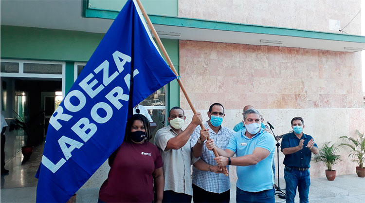 De la manos de Izquierdo Alonso y Ramírez (en el centro), Yunaika y Miguel Paz recibieron la bandera de Proeza Laboral. Foto: Noryis