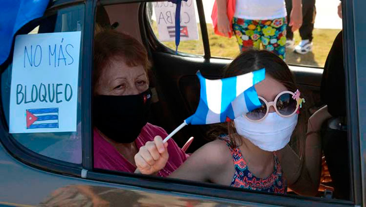 Una niña muestra una bandera cubana mientras recorren en un auto el emblemáticos Malecón de La Habana en una singular caravana que demandó el fin del bloqueo que desde hace más de medio siglo mantiene Estados Unidos contra la isla, en La Habana, el 28 de marzo de 2021. Foto: Joaquín Hernández Mena/Trabajadores