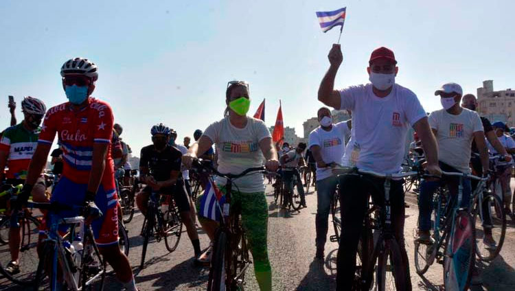 Ciclistas circulan ondeando banderas cubana mientras recorren el emblemáticos Malecón de La Habana en una singular caravana que demandó el fin del bloqueo que desde hace más de medio siglo mantiene Estados Unidos contra la isla, en La Habana, el 28 de marzo de 2021. Foto: Joaquín Hernández Mena/Trabajadores