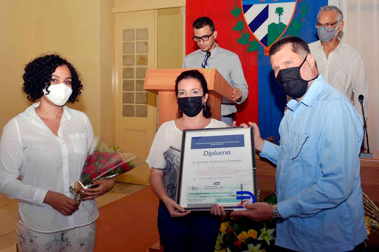 Oscar Luis Hunt Pentón, presidente de la Asociación Nacional de Economistas de Cuba (Anec), pone el diploma acreditativo del premio en periodismo radial en las manos e Laura Brunet Nodarse y premiada Gretta Espinosa Clemente, de la emisora cienfueguera Radio Ciudad del Mar. Foto: Modesto Gutiérrez/ACN
