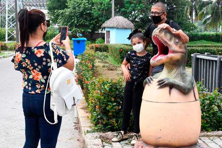 Una madre le toma una fotografía a sus hijos frente a un reptil exhibido en el parque temático de dinosaurio, en La Habana, el 31 de octubre de 2021. Foto: Joaquín Hernández Mena/Trabajadores