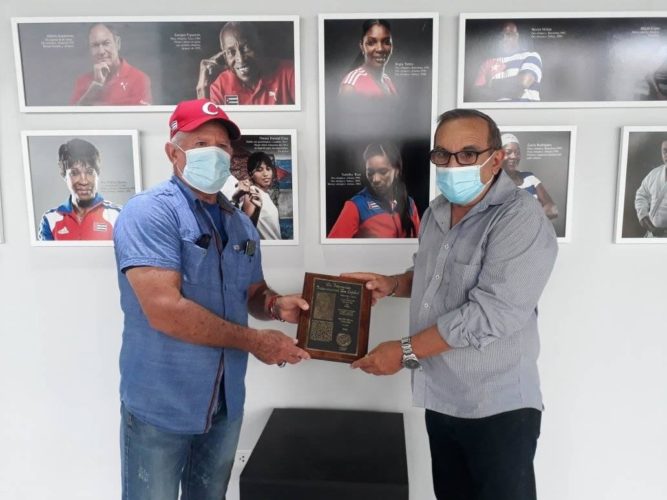 Armando hace entrega de la placa al director del Salón del Deporte Cubano, Erie Reyes.