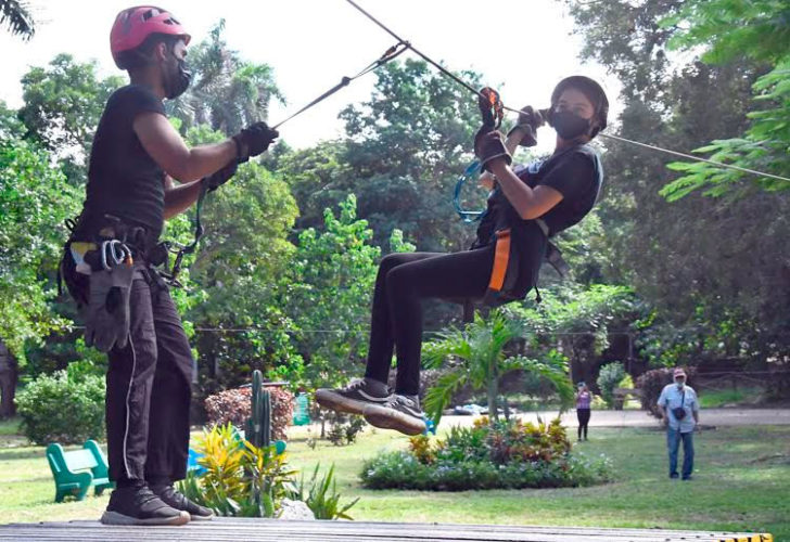 Un guía (I) recibe en una de las estaciones a una joven que disfruta de un salto del canopy tour en el Parque Ecológico de La Habana, conocido popularmente como "Monte Barreto", en La Habana, el 6 de noviembre de 2021. Foto: Joaquín Hernández Mena/Trabajadores