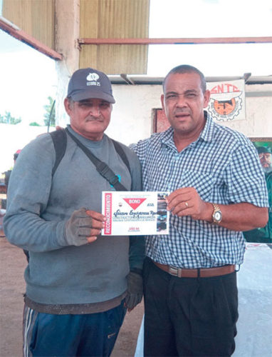 El secretario general de la CTC en Matanzas (a la derecha) entrega a Lázaro el bono de ganador en el movimiento emulativo Constructores Todo por Cuba. Foto: Noryis